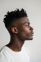 Obraz premium Side profile of a young man displaying a trendy tapered fade hairstyle against a neutral background
