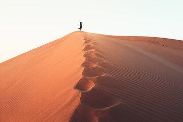 Woman silhouette enjoy sand dunes in desert in sunset blue hour alone. Travel lifestyle and...