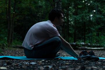 Young handsome man doing yoga in lotus position in the wood. Training and sport on nature concept	