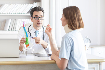 Male doctor orthopedist explaining to his female patient with serious neck injury in neck brace about importance of cervical collar for healthy cure