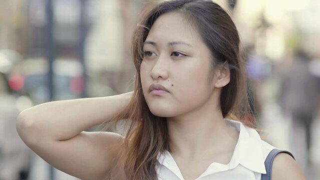 pensive young Asian woman portrait in the street 