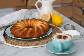 Ring of lemon sponge cake with cappuccino for an afternoon snack.