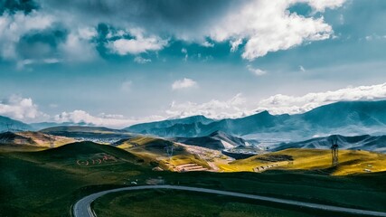 Aerial photograph of Riyue mountain, a road, and yellow fields in China under the shadow of clouds.