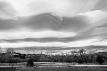 Grayscale shot of bright moody cloudscape over the arid field in New Zealand