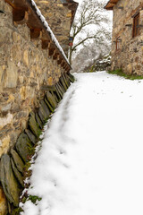 row of slate tiles stacked on the wall of a stone farmhouse in a snowy mountain village
