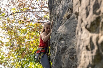 Naklejka na ściany i meble Girl climbing a cliff. Rock climbing, sport concept.