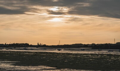 Boats on the seaside at sunset with an orange cloudy sky in the background