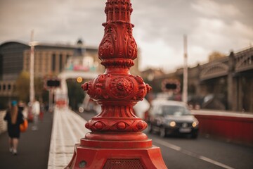 Closeup of a red fire pole against the blurred busy road - obrazy, fototapety, plakaty