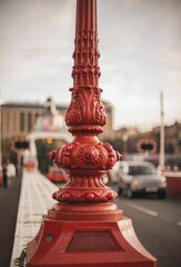 Closeup of a red fire pole against the blurred busy road