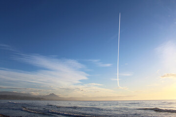 a trail of an airplane in the sky above the sea