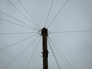 Fototapeta premium Low-angle shot of a telecommunications pole with wires on a cloudy day