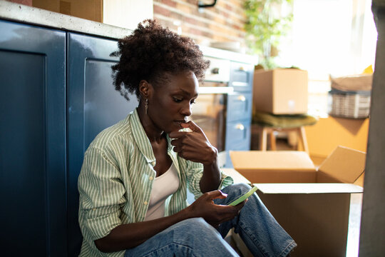 Woman using smartphone on floor with moving boxes around