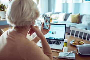 Elderly woman in telehealth session with doctor on smartphone at home
