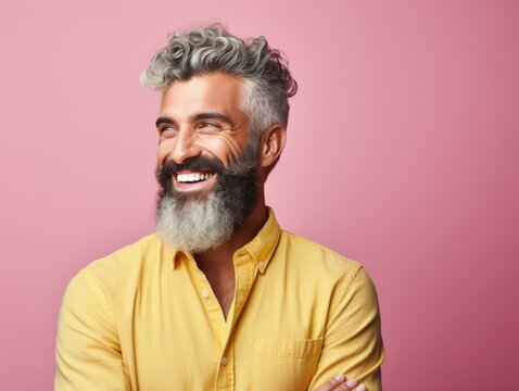 A man with a beard and a yellow shirt is smiling