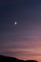 Vertical shot of the crescent moon in the sky at sunset