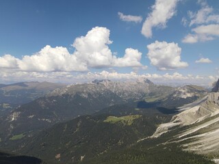 Aerial of a vast valley with floating clouds above in the Alps of Italy