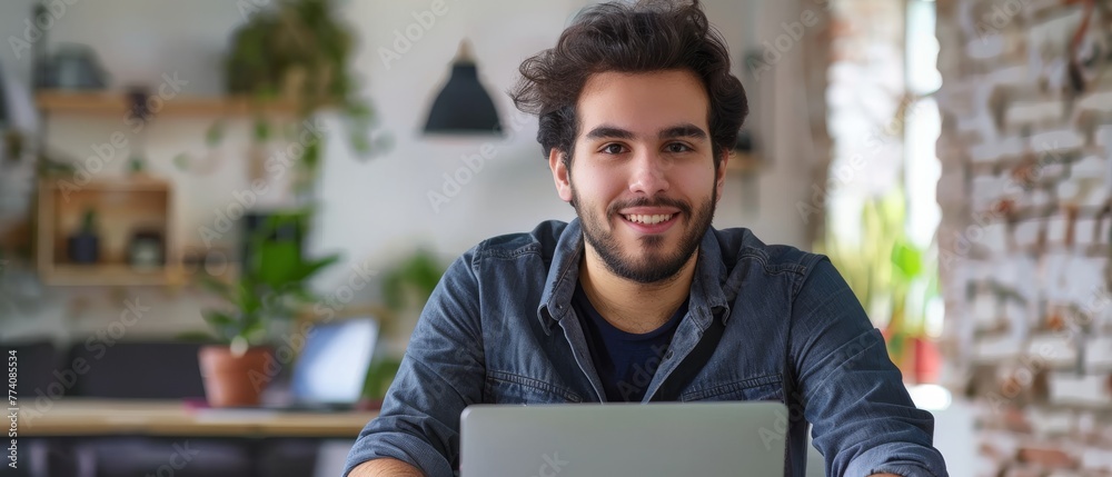 Poster an attractive hispanic businessman works on a laptop, analyzes data and looks into the camera while 