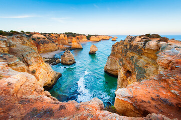 Rocks on the shore of Atlantic ocean in Algarve, Portugal. Summer seascape at sunset. - obrazy, fototapety, plakaty
