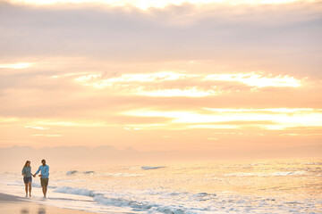 Couple In Casual Clothing On Vacation Holding Hands Walking Along Beach Shore At Dawn