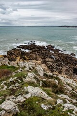 Vertical shot of a rocky shore during the tide under a cloudy sky