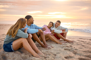 Young Couple With Friends In Casual Clothing On Vacation Sitting On Beach Watching Sunrise Together