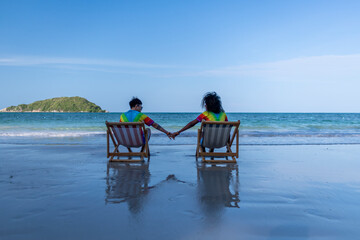 Happiness couple LGBTQ lover sitting on beach chair holding hand show happiness with equality...