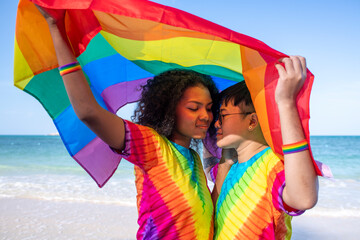 Happiness Lesbian LGBTQ couple holiday summer on the beach with show a rainbow flag a symbol of the...