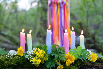 colorful magic candles and flowers in forest, natural background. Witch ritual for Beltane or Litha sabbat. Midsummer. Witchcraft, esoteric spiritual practice, divination. mysterious fairy scene - obrazy, fototapety, plakaty