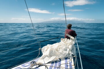 Man sitting on the bow of a ship sailing in the ocean