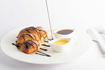 Closeup of a croissant with dripping chocolate served with sauces