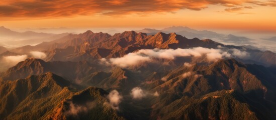 Aerial view of mountains in orange clouds at sunset in summer.