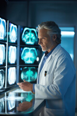 Mature doctor analyzing MRI brain images in medical office - 774094189