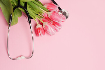 Stethoscope with bouquet of tulips on pink background, copy space