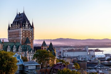 Obraz premium Beautiful view of the Chateau Frontenac surrounded by greenery in Quebec, Canada at sunrise