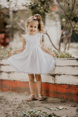 Cute little girl in white dress, posing and smiling - 774097515