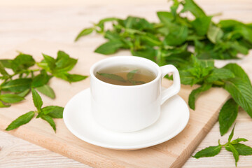 Cup of mint tea on table background. Green tea with fresh mint top view with copy space