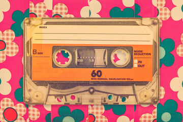 Vintage orange audio compact cassette in front of a background with flower pattern - 774106921