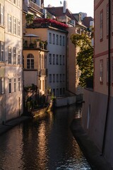 Vertical of the Certovka canal between buildings in Prague in the morning during sunrise
