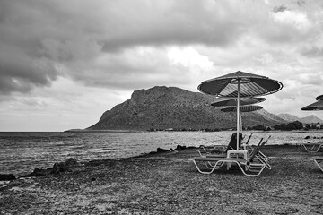 Umbrellas on the rocky beach on a cloudy day in Stavros on the island of Crete
