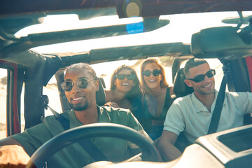 Young Couple With Friends On Vacation Inside Car Driving On Road Trip Adventure To Beach