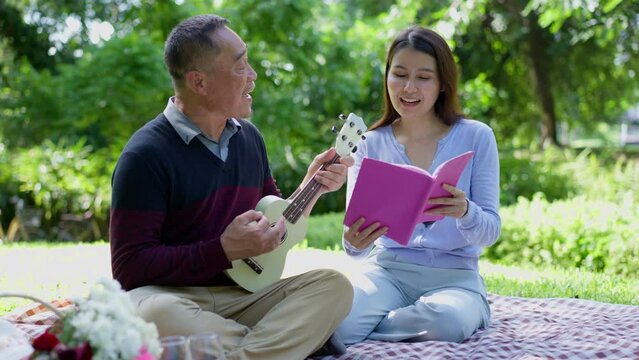 Daughter comes to visit parents and picnic in park, family, leisure and people concept - happy fathers, elderly caregiver, enjoying outdoor on picnic blanket reading book in park at sunny time
