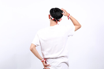 Back view of confused Young asian boy with red white ribbon celebrating Indonesia independence day...