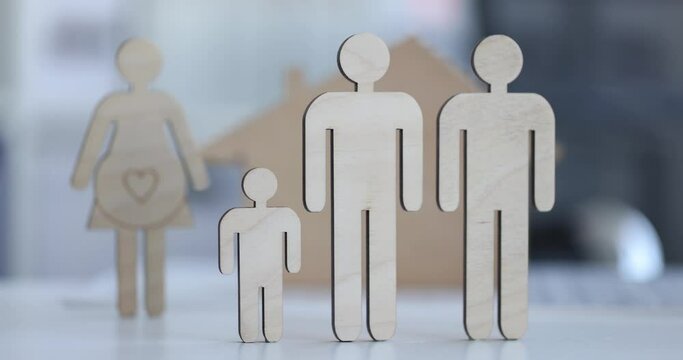 Two figurines of wooden men with child on background of pregnant woman. International IVF and surrogacy agency concept