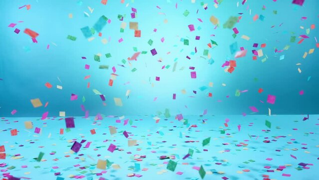 Multicolored confetti falling on blue background, anniversary, birthday or wedding celebration