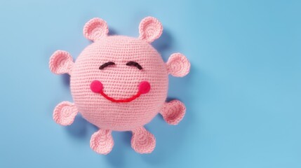 Knitted, cute pink sun with a smile on a blue background, top view, with space for text. Greeting card, hobbies, knitting, children's toys.