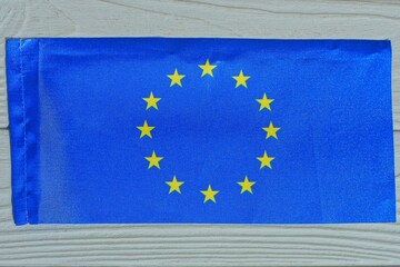 one blue small with yellow stars small flag of the European Union lies on a wooden  gray table

