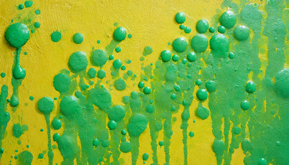 Green paint drops, splatters on textured yellow wall. Abstract background. Art brush stroke.