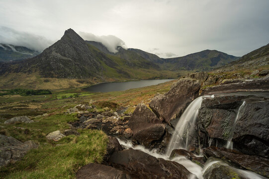 Small Waterfall with Tryfan and lake Ogwen in the background on a cloudy day, Snowdonia National Park, North Wales, UK.