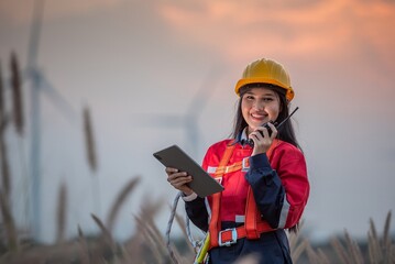 Woman engineer inspection posing check control wind power machine in wind energy factory at silhouette sunset. girl technician professional worker check wind power machine for maintenance turbine