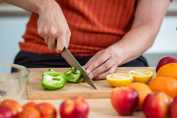 Hand chef knife cut and slice fresh Vegetables baby cos salad on wood board table .Make Salad Organic Vegetables mix lunch with green vegetables and fruit at kitchen table on wood cutting board.